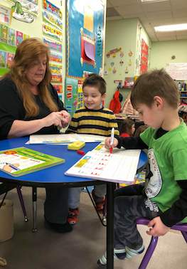 Teacher helping kids to learn writing